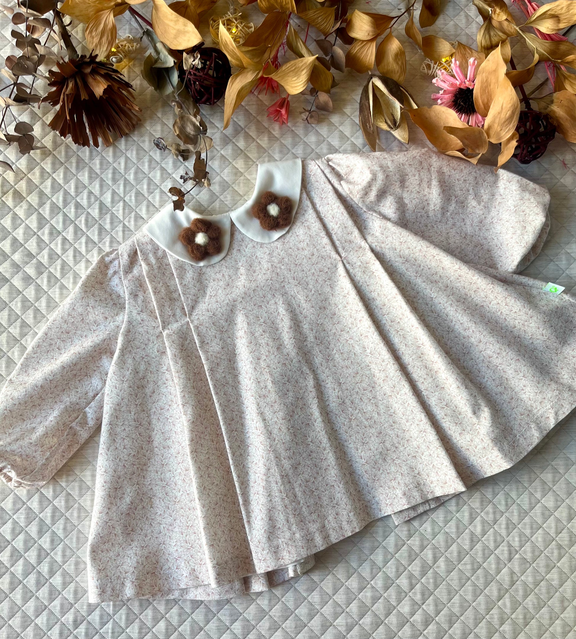 Vestito_svasato_con_pieghe_e_colletti_con_fiori_applicati_davanti